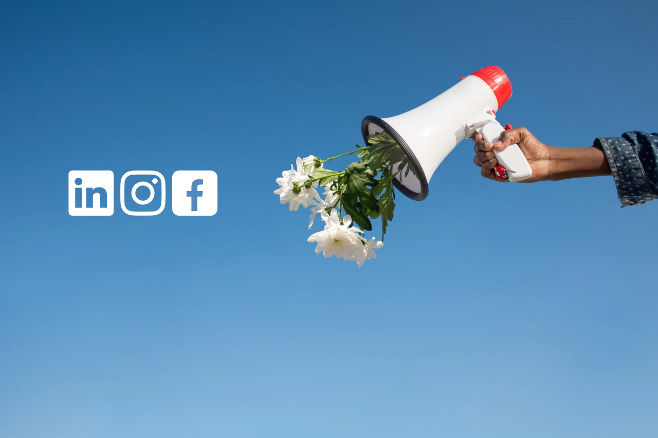 na tle niebieskim - z prawej strony ręka trzymająca megafon z którego wystają białe kwiaty, na lewo od megafonu ikony linkedin, instagram, facebook