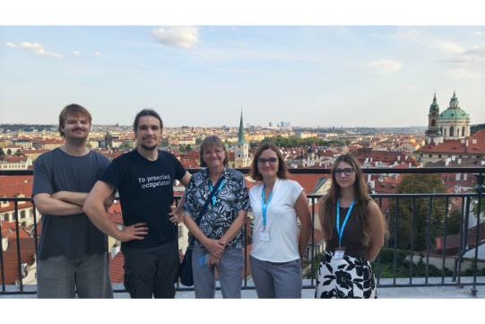 5 osób pozuje do zdjęcia na tle panoramy miasta