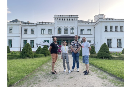4 osoby stoją przed białym budynkiem