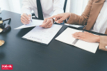 two people at the desk, checking the documents
