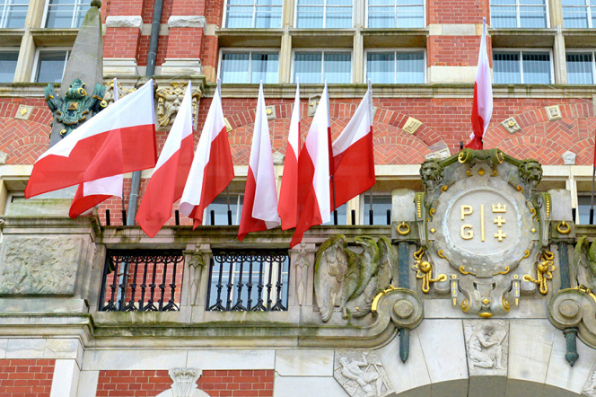 Na zdjęciu widoczny fragment Gmachu Głównego z kartuszem i biało-czerwonymi flagami nad wejściem głównym