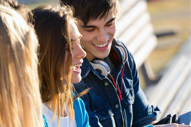 zdjęcie przedstawia dwoje młodych ludzi, widać uśmiechniętą twarz chłopaka i uśmiechniętą dziewczynę sfotografowanąz profilu