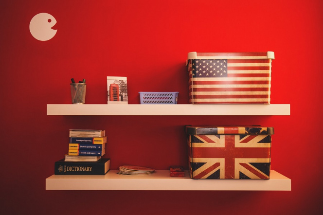 dwie półki na czerwonej ścianie a na nich flaga amerykańska i brytyjska 