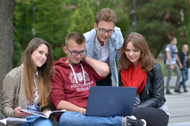 zdjęcie przedstawia grupę studentów siedzących przed laptopem