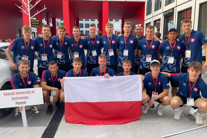 W dwóch szeregach grupa młodych mężczyzn. Na przedzie trzymają flagę Polski.
