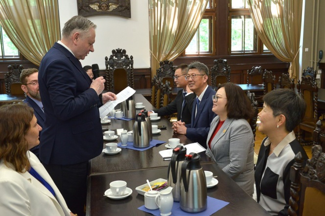 Rektor Sienkiewicz przemawia do gości zgromadzonych przy stole podczas spotkania z delegacją z Azji