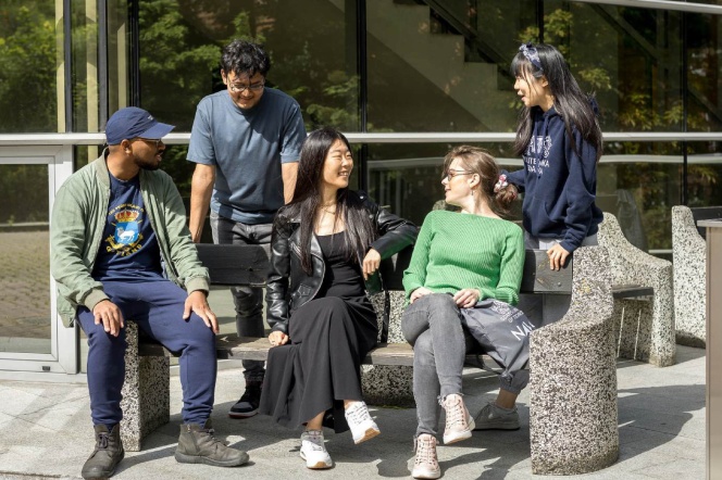international students sitting on the bench in front of the builiding