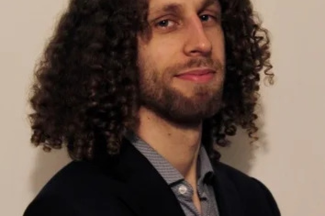 Na zdjęciu mężczyzna z lokowanymi włosami