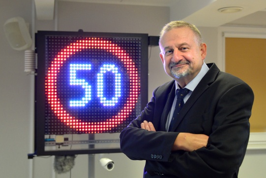 na zdjęciu prof. Andrzej Czyżewski, w tle wyświetlacz ze znakiem ograniczenia prędkości do 50 km/h