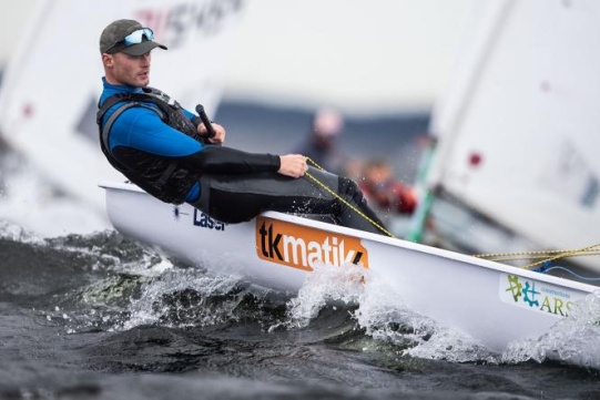 In the photo, there is Filip Ciszewski, vice-champion of senior Europe in the Olympic Laser Radial class. He is in a sailing boat at sea among waves.
