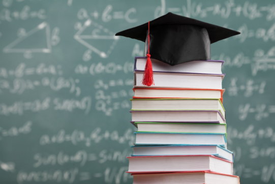 Biret studencki na stercie książek 