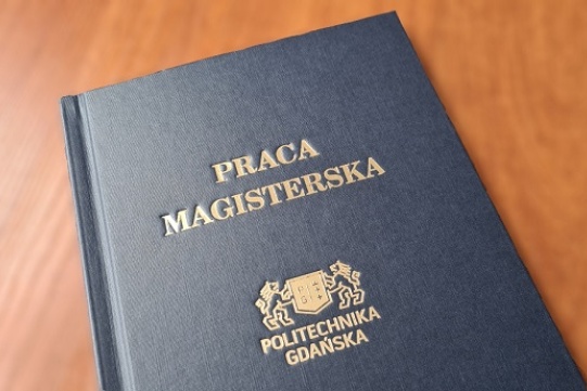 The photo shows a master's thesis framed in a navy blue binding with golden inscriptions. The copy is placed on a wooden table.