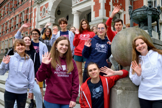grupa uśmiechniętych studentów przed gmachem głównym PG