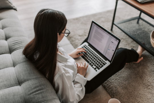 The picture shows a woman with a laptop on her knees
