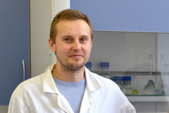 na zdjęciu widoczny jest dr inż. Mariusz Szkoda ubrany w biały kitel oraz jasno niebieską bluzkę.