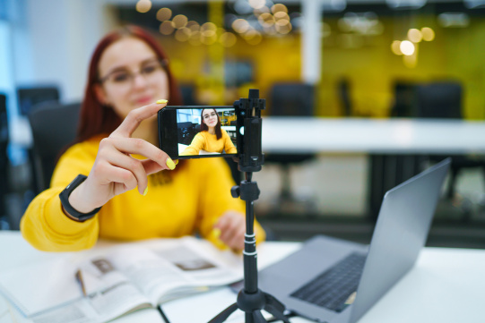 Dziewczyna w żółtej bluzie trzymająca telefon 