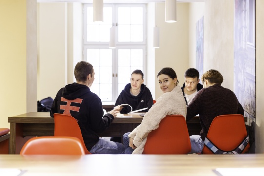 Na zdjęciu widac grupę studentów przy stole. 