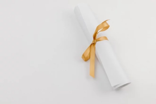 The photo shows a white card with a gold ribbon laid on a white background.