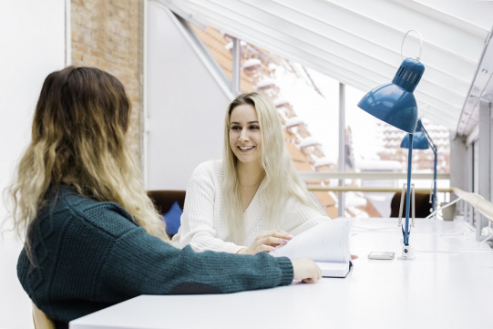 Na zdjęciu widać dwie rozmawiające ze soba studentki. 