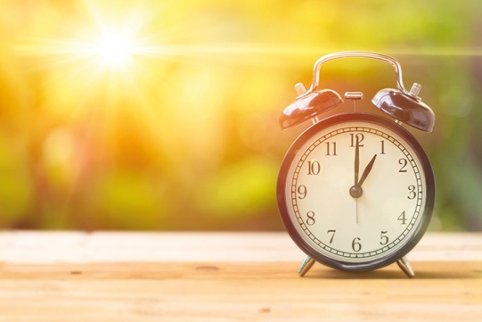 Zegarek, budzik na tle słonecznego krajobrazu