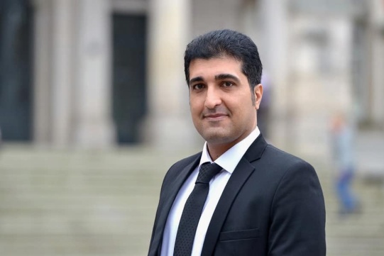 Pan Mohammad Malikan w czarnym garniturze na tle Gmachu Głównego PG 