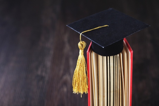 Black graduate cap lying on the book.