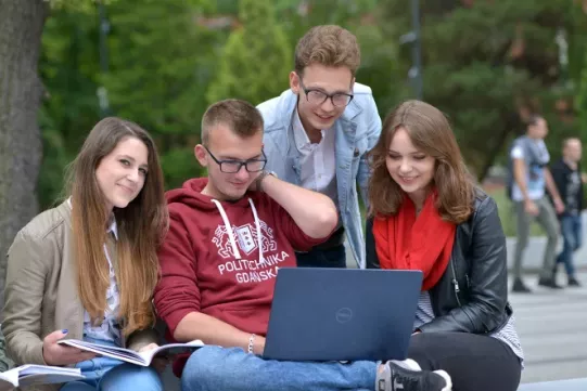 zdjęcie przedstawia grupę studentów siedzących przed laptopem