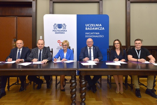 Porozumienie podpisali (od lewej): prof. Mirosław Wołoszyn, dziekan WEiA, prof. Jacek Stefański, dziekan WETI, prof. Małgorzata Gawrycka, dziekana WZiE, prof. Krzysztof Wilde, rektor PG, prof. Joanna Żukowska, dziekana WILiŚ oraz Patryk Żyła kierownik Biura Projektów Strategicznych PG. Fot. Krzysztof Krzempek/PG