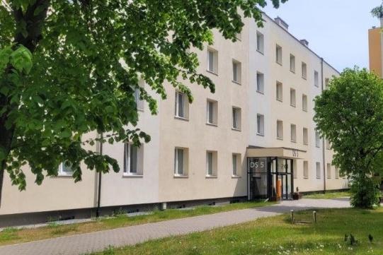 Zdjęcie przedstawia budynek domu studenckiego nr 5 zza drzew.