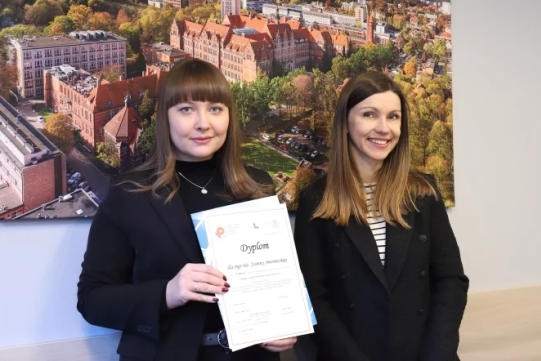 Na zdjęciu znajdują się dwie kobiety ubrane na ciemno