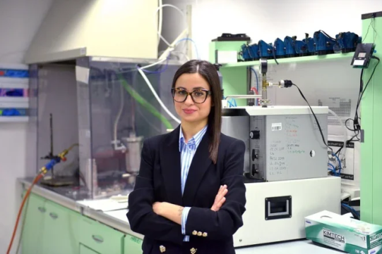 Na zdjęciu znajduje się kobieta w laboratorium, na tle aparatury