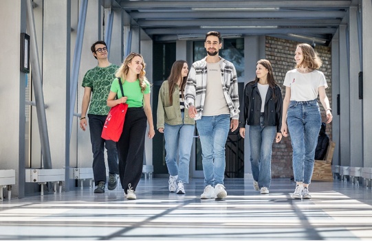 studenci idą przez łącznik pomiędzy budynkami