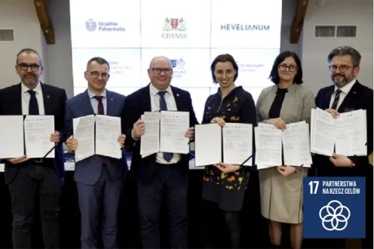 The photo shows people holding a signed cooperation agreement between Fahreinheit Universities and Hevelianum