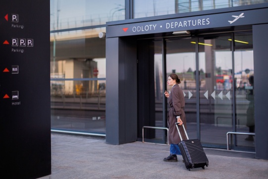 Dziewczyna z walizką przed wejściem na lotnisko