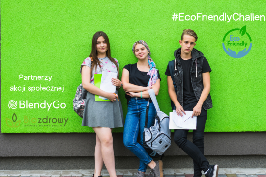 Na zdjęciu na zielonym tle trzy osoby siedzące na ławce