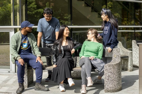 international students sitting on the bench in front of the builiding