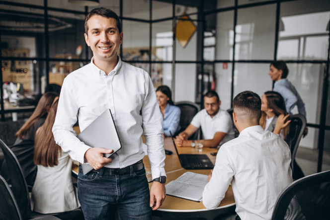 Businessman standing in startup office with young people team in the background