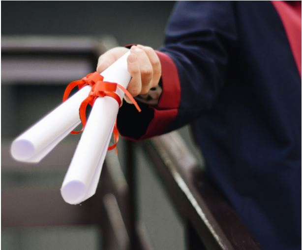 Dwa dyplomy w ręku absolwenta