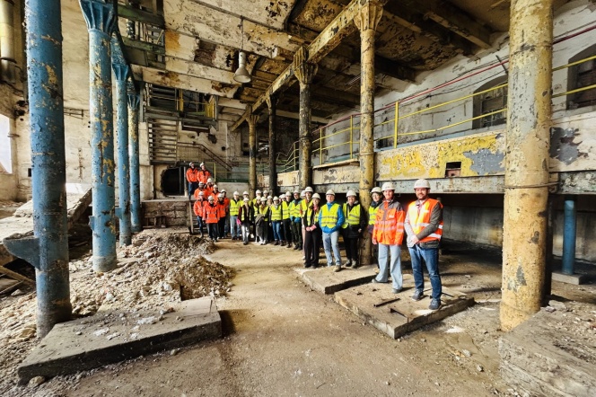 Studenci kierunku budownictwo w kaskach i odzieży ochronnej stojący we wnętrzu zabytkowego obiektu dawnej Cukrowni w Pruszczu Gdańskim podczas wizyty na placu budowy.
