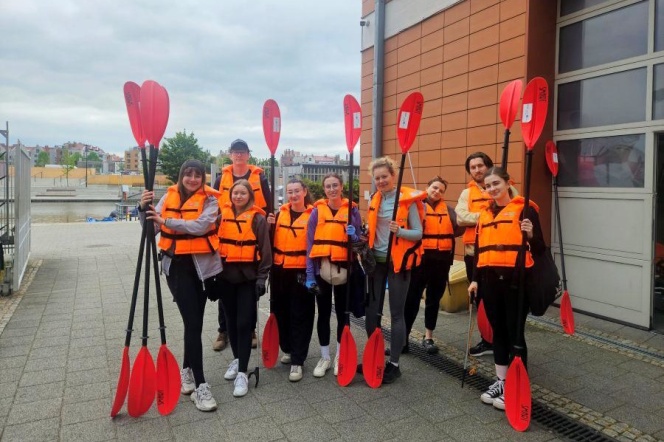  Studenci Inżynierii Środowiska podsumowali zajęcia w terenie. Studenci w kamizelkach ratunkowych trzymających wiosła, przygotowujących się do spływu wodnego.