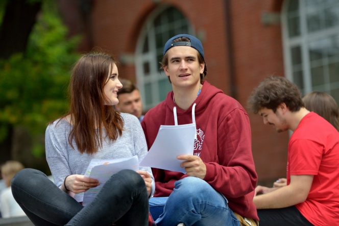 Two students with the main building of Gdansk University of Technology