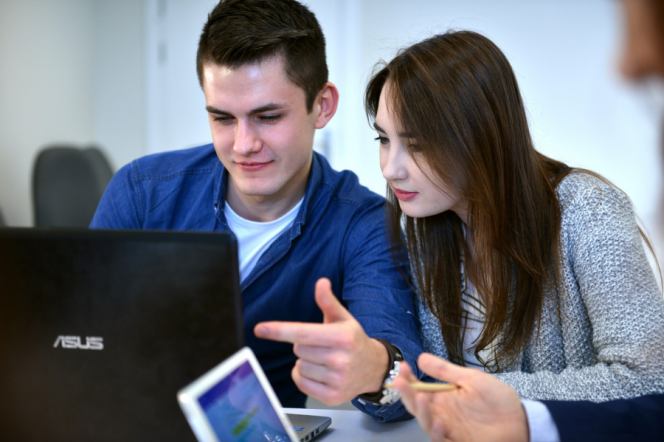 Student wskazujący na ekran laptopa, obok którego siedzi studentka